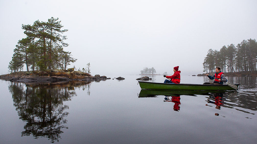 People are paddling a canoe on a foggy lake.