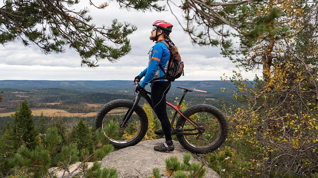 A mountain biker admires the autumn landscape from the top of the hill.