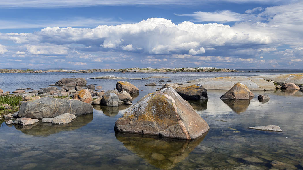 Clear water, large rocks in the foreground. Cloudy skies.