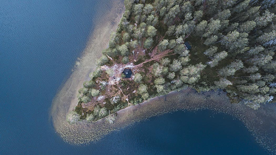 Kylmäluoma hiking area photographed from the air. A hut surrounded by a forest at the tip of a cape.