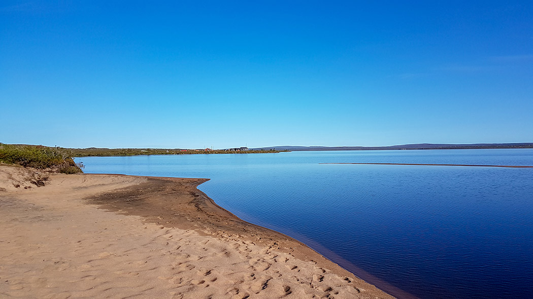 A beach at the lake Pöyrisjärvi. Far in the distance there are houses by the shore.