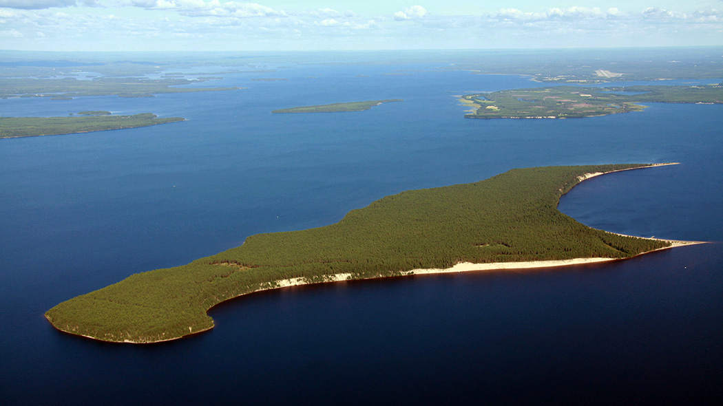 Aerial view of an island surrounded by a large lake in summer. Further afield other islands.