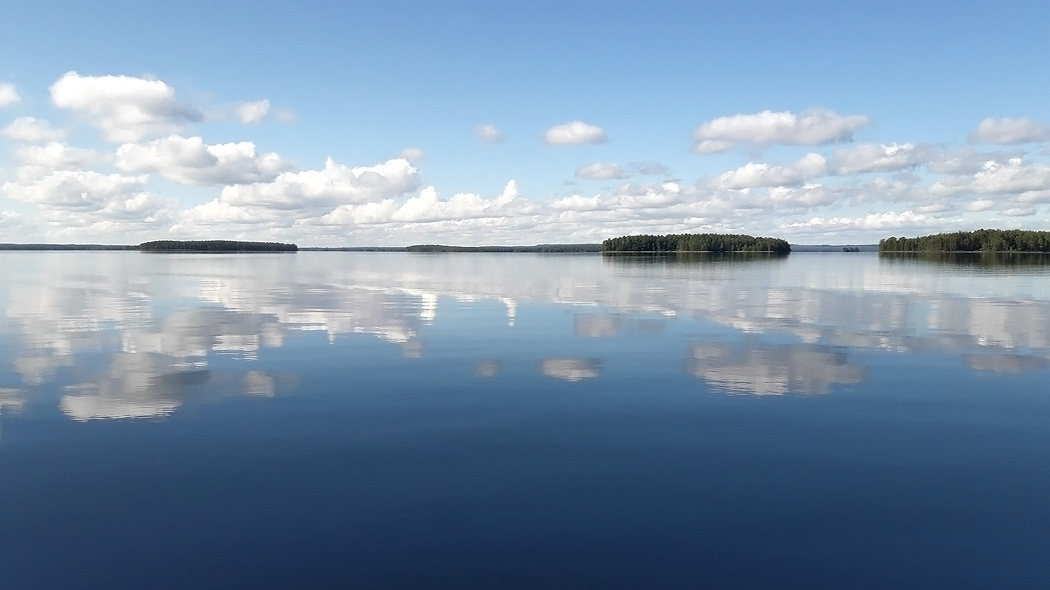 A calm lake. Islands with forest in the background.
