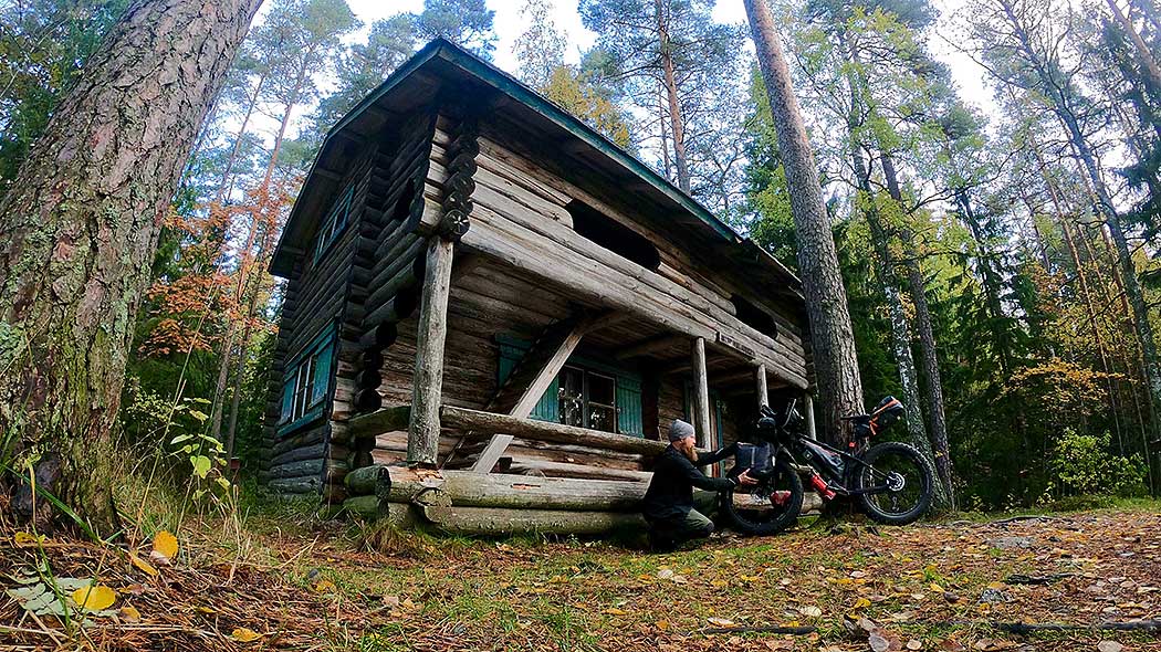 The hut from outside. Outside the hut, a man is packing things on a mountain bike.