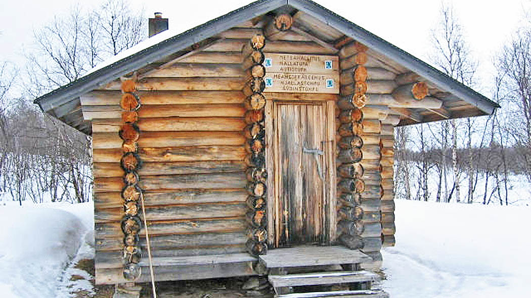 Nallatupa open wilderness hut in winter. The hut is slightly elevated from the ground, and wooden steps lead to the door.