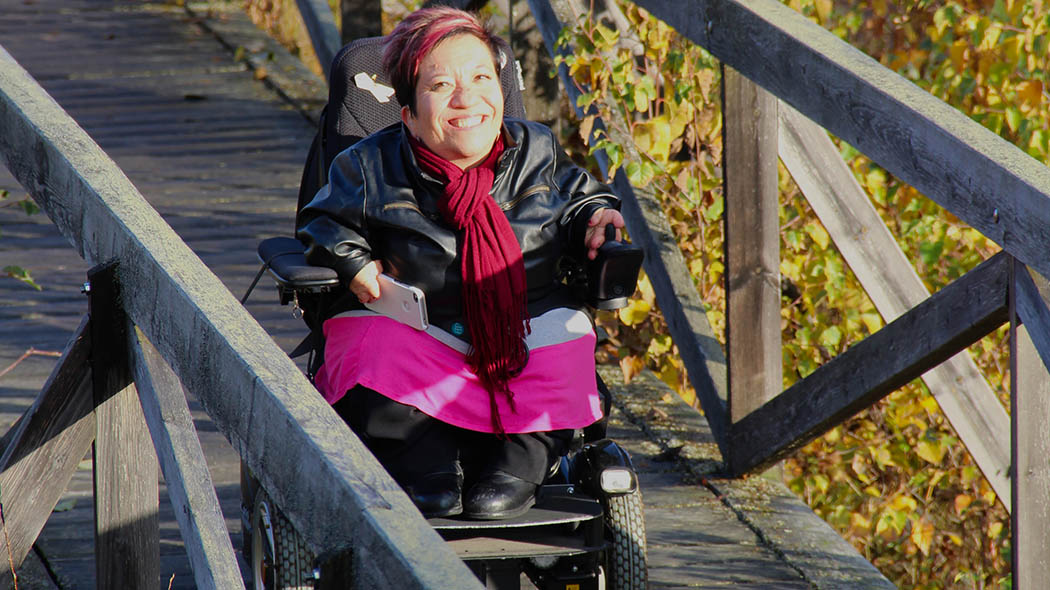 A hiker in the wheelchair climbing a ramp in the sunny autumn breeze.